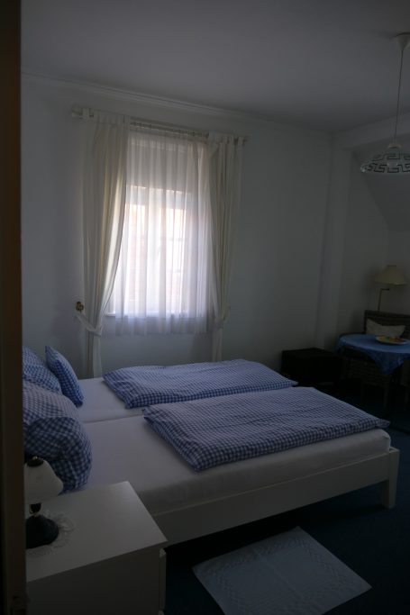 Helles Schlafzimmer mit zwei Einzelbetten, blauen Bettdecken und einem Fenster.