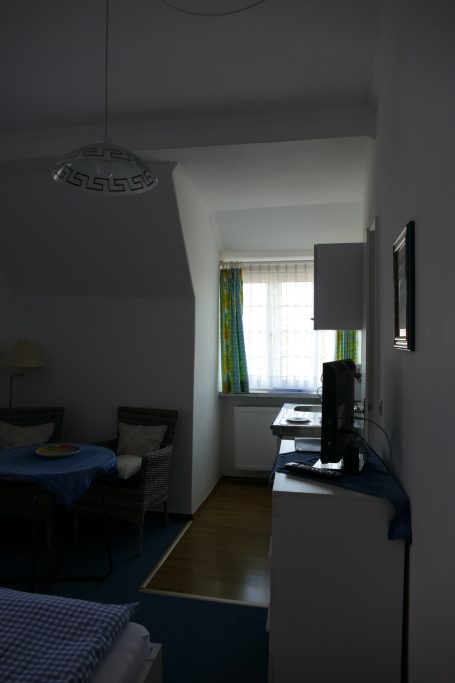 Ein heller Raum mit einem Fenster, Tisch, Stühlen und einem Lampenständer.